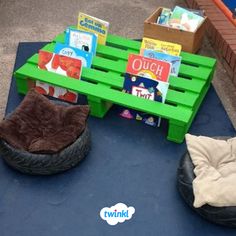 some books are sitting on top of a green pallet and there is a dog bed next to it