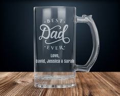 a glass mug with the words best dad ever on it sitting on a wooden table