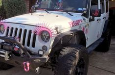 a white jeep parked in front of a brick building with pink decorations on the side