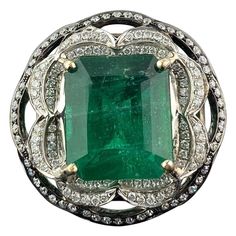 A very unique 18K Black Rhodium and White Gold cocktail ring, with a natural 6.54 carat natural Zambian Emerald center stone and White Diamonds. The Emerald is of high quality, ideal vivid green color and great luster. The ring is currently sized at US 6.5, can be changed. We provide free shipping, and returns are accepted! Luxury Dazzling Emerald Ring With Center Stone, Luxury Gold Emerald Ring With Exquisite Style, Luxury Green Rings With Intricate Design, Emerald Engagement Ring Vintage, Antique Emerald Ring, Vintage Emerald Engagement Ring, Wedding Ring Unique, Natural Emerald Rings, Emerald Wedding Rings