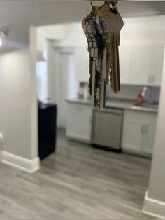 a bunch of keys hanging from the ceiling in a room with white walls and wood flooring