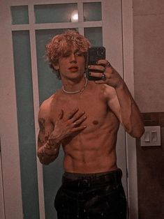 a shirtless man taking a selfie in front of a mirror with his hands on his chest