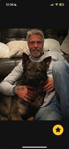 a man sitting on top of a couch holding a german shepard dog in his lap