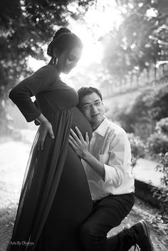 a man and woman pose for a black and white photo in front of some trees