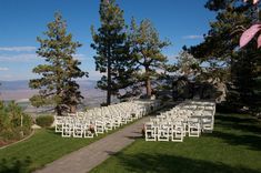 rows of white chairs are set up for an outdoor wedding ceremony in the mountains above lake tahoe