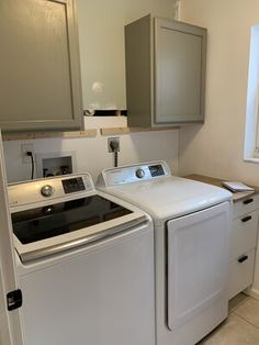 a white washer and dryer in a small room with cabinets on the wall