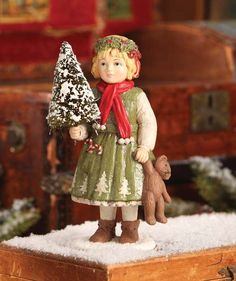 a small figurine holding a christmas tree and a teddy bear