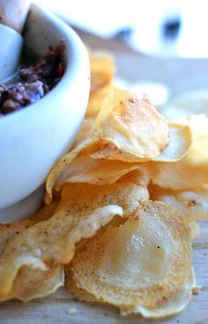 some chips are sitting next to a bowl of chili and tortilla chips on a table