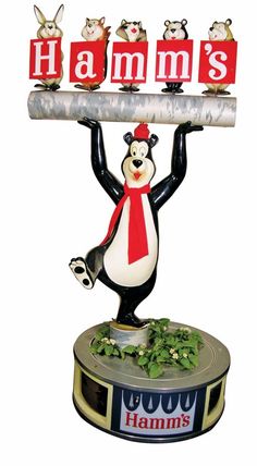 a sign that says hamm's on top of a penguin holding a piece of wood