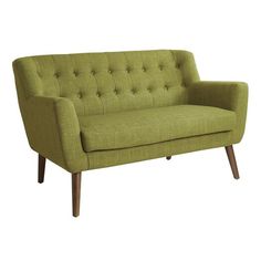 a green couch sitting on top of a white floor next to a wooden leg chair