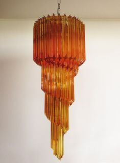 an orange chandelier hanging from a ceiling in a room with white walls and flooring