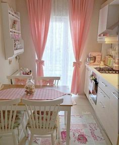 a dining room table and chairs with pink curtains