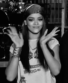 a woman with long hair wearing a bandana and holding her hands up in front of her face