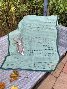 a blanket with a bunny on it sitting on top of a bench next to leaves