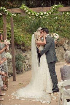 a bride and groom kissing in front of an outdoor ceremony