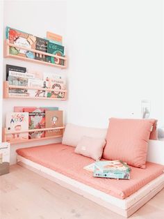 a bed that has some books on top of it in a room with white walls