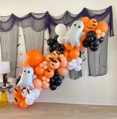 an assortment of halloween balloons in the shape of cats and ghostes hanging on a wall