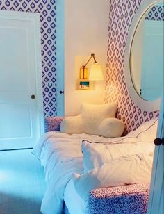 a white bed sitting in a bedroom next to a mirror on the side of a wall