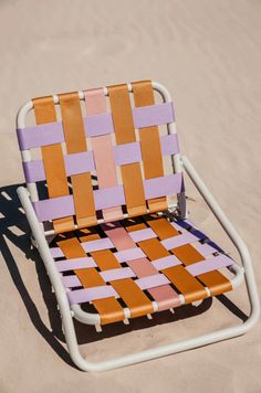 a colorful lawn chair sitting in the sand