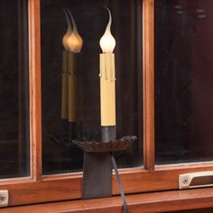 two lit candles sitting on top of a window sill