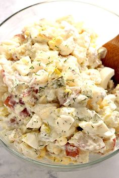 a glass bowl filled with potato salad and a wooden spoon