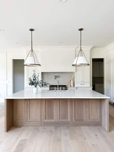 a large kitchen island with two pendant lights over it's head and an oven in the background