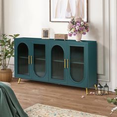 a living room with a blue cabinet and flowers on the table in front of it