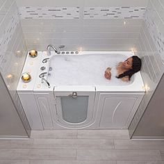 a woman laying in a bathtub with candles around it