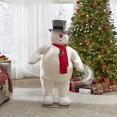 a large inflatable snowman standing next to a christmas tree