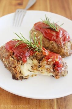 meatloaf stuffed with cheese and sauce on a white plate next to a fork