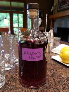 a bottle of blackberry liqueur sitting on top of a counter next to glasses