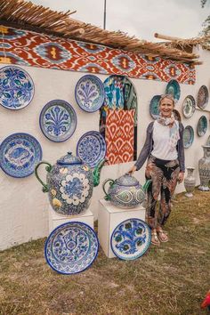 a woman standing in front of some blue and white vases