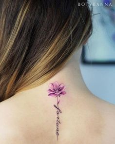 a woman's back neck with a flower tattoo on it