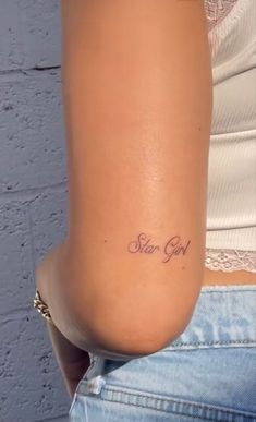 a woman with a small tattoo on her lower back and the words star girl written in cursive font