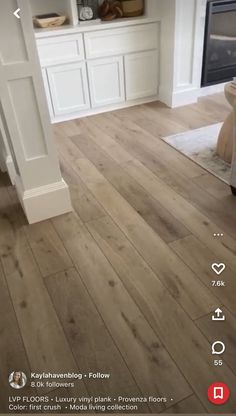 an image of a living room with wood floors and white cabinets in the back ground