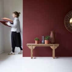 a woman holding a frisbee standing next to a table with potted plants on it