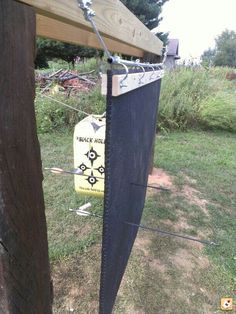 a wooden post with a sign attached to it in the grass next to a fence