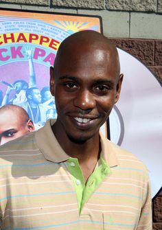 a man standing in front of a movie poster and smiling at the camera with his hand on his hip