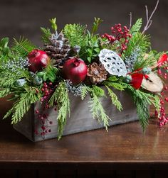 a wooden box filled with pine cones and pomegranates on top of a table