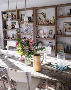 a table with flowers and vases on it in the middle of an open room