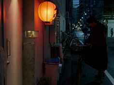 a man standing next to a building with a bike parked on the side of it