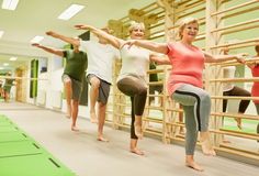 three women are practicing yoga in an indoor area with green mats and wooden railings