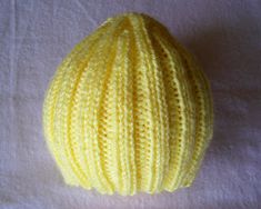 a yellow knitted ball sitting on top of a white sheet