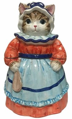 a ceramic figurine of a cat wearing a dress and hat, holding a purse