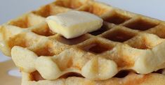 a stack of waffles topped with butter on top of a white plate next to a fork