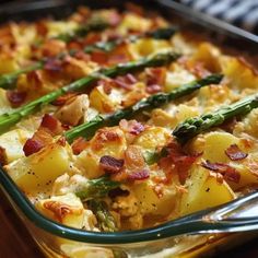 a casserole dish with potatoes, asparagus and bacon on it is ready to be eaten