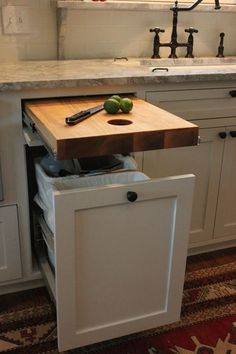 a kitchen with a cutting board and knife on the counter top next to an open drawer