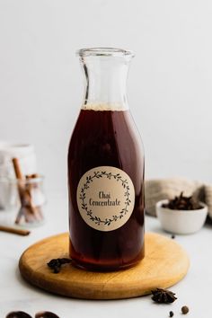 a glass bottle filled with liquid sitting on top of a wooden board next to some nuts