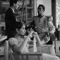 an old black and white photo of a woman sitting in a chair with a man standing behind her