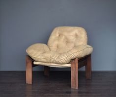 a chair sitting on top of a hard wood floor next to a gray wall and wooden legs